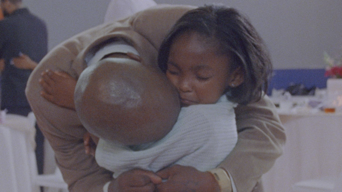 man leaning down to hug young girl