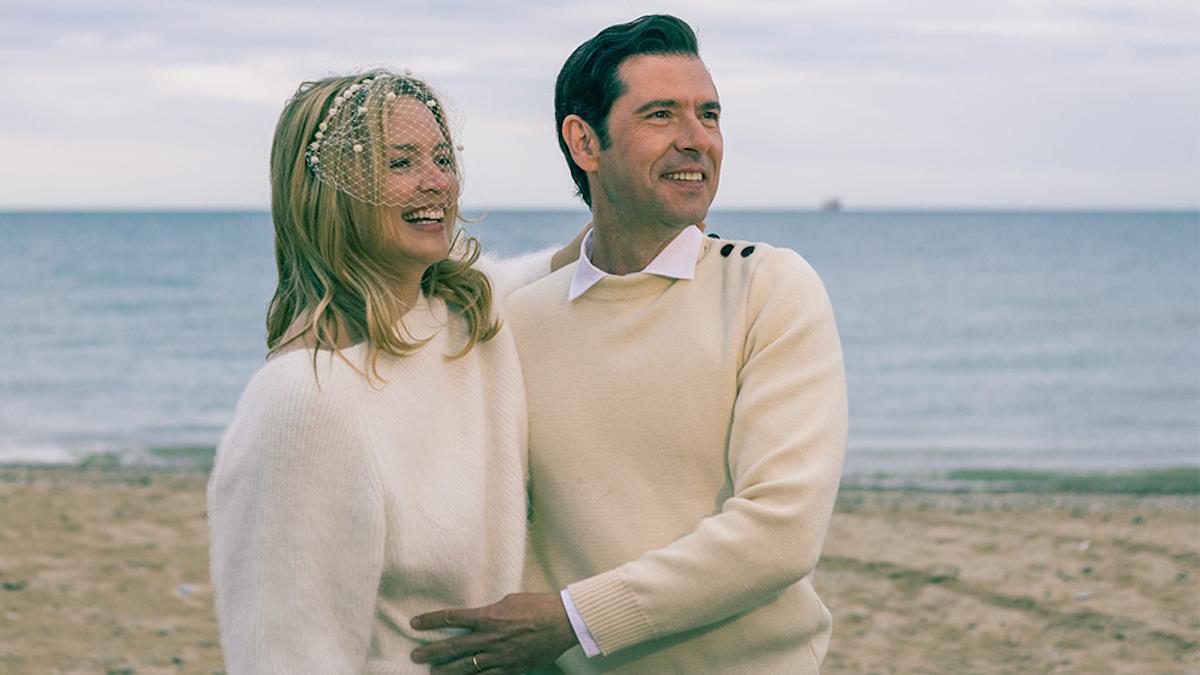man and woman wearing beige sweaters standing on beach arm in arm